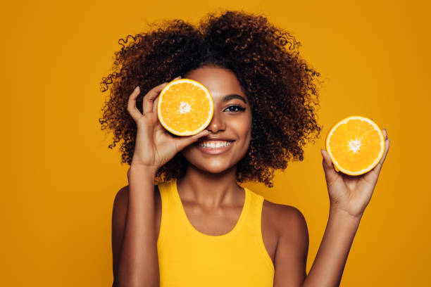 hermosa chica afro con una naranja - vitamin c fotografías e imágenes de stock