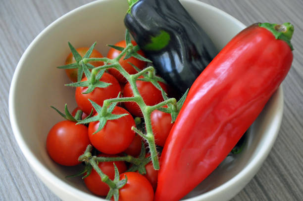 istock On the vine Cherry tomatoes in a bowl with two sweet ppers 1287400795