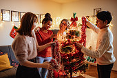 クリスマスと元旦のクリスマスとクリスマスの間に自宅で若い日本人とアフリカ系アメリカ人の友人がクリスマスツリーを飾る