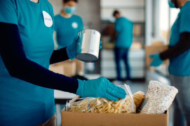 unrecognizable volunteer packing donated food in cardboard box. - banco alimentar imagens e fotografias de stock