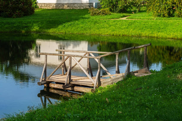 Wooden panked footway on the bank of a small pond in the park of the Petrovskoye estate on a bright sunny day.