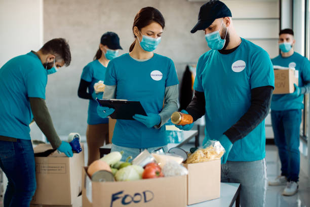 istock Volunteers cooperating while packing donation boxes for food charity. 1287406480