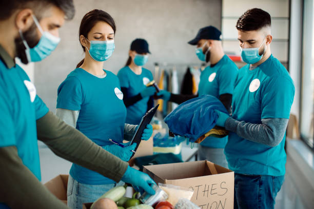 istock Group of people working in charitable foundation and packing donation boxes. 1287406818