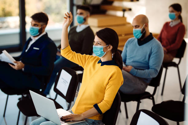 istock Businesswoman with raising her arm to ask a question while attending a seminar during coronavirus pandemic. 1287408299