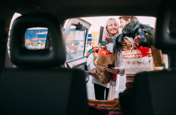 A young couple in love packing Christmas gifts in a car after shopping for the holidays.