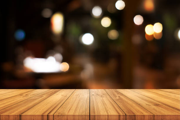 istock Empty wooden table top with blurred coffee shop or restaurant interior background. 1287411394