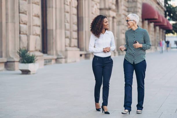 imprenditrici che camminano fianco a fianco per strada - leadership business women senior adult foto e immagini stock