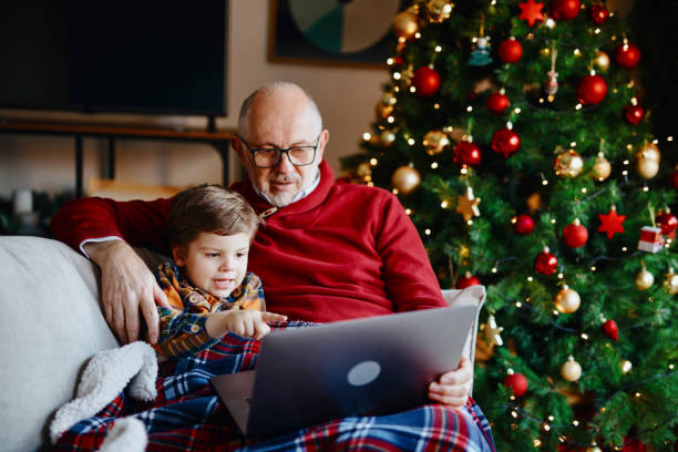 liebender großvater genießt zeit mit seinem enkel zu hause beobachten cartoons auf laptop - family domestic life senior adult computer stock-fotos und bilder