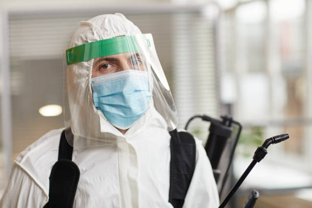 Disinfection Worker Portrait of male disinfection worker wearing full protective gear and looking at camera while sanitizing office, copy space biohazard cleanup stock pictures, royalty-free photos & images