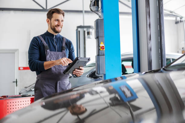 istock Mechanic using tablet for diagnosing a car issue. Garage of car salon interior. 1287417825