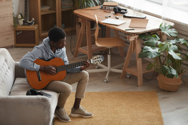 istock Young African-American Man Playing Guitar at Home High Angle 1287419258