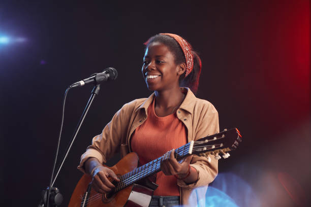 istock African-American Woman Playing Guitar on Stage 1287419323