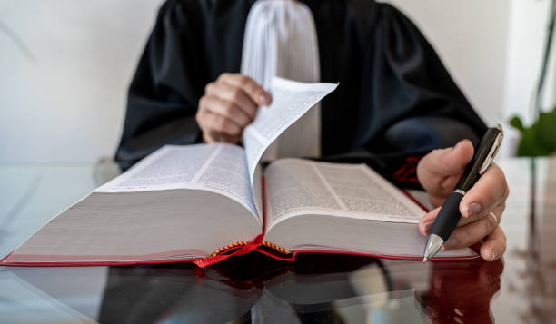 istock Justice, lawyer holding and reading open red law book 1287419925