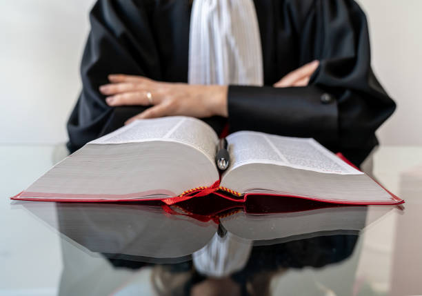 justiz, anwalt halten und lesen offenes rotes gesetzbuch - richter robe stock-fotos und bilder