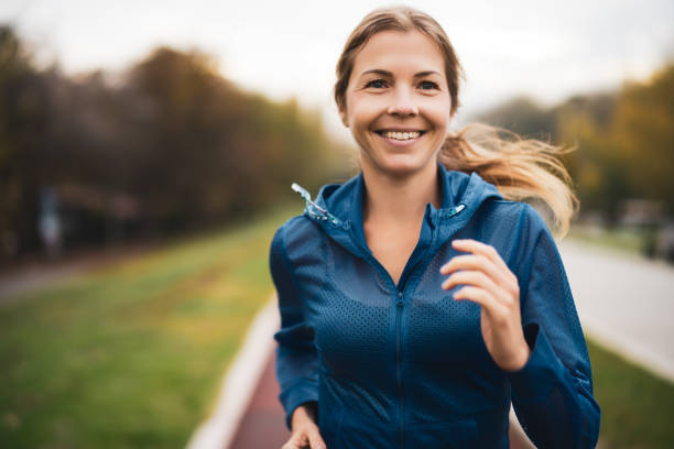 Sports training Beautiful adult woman is jogging outdoor on cloudy day in autumn. active lifestyle stock pictures, royalty-free photos & images
