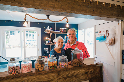 A shot of a senior Couple standing behind the counter in a coffee shop ready to serve customers.