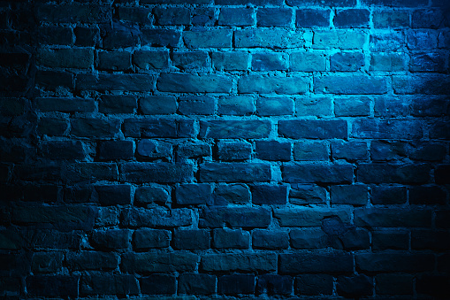 Horizontal background of empty brick wall with blue neon lighting effect, copyspace ready for design, wallpaper, advertising. House wall in close-up. Stylish flyer for ad, offer, bright colors.