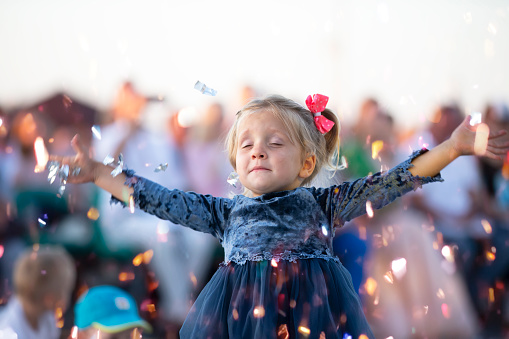 A funny little girl scatters sparkles on a holiday.