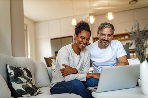 Two adults, smiling, browsing something online.