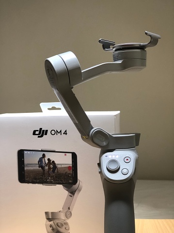 DJI OM4 Smartphone Gimbal, Cape Town, South Africa - 23 November, 2020: The new DJI OM4 Smartphone Gimbal is a foldable stabiliser for smartphones that was launched worldwide at the end of August 2020.  It features the new magnetic phone clamp for easier storage and usability.  On this image it features the gimbal with magnetic clamp and the packaging box.
