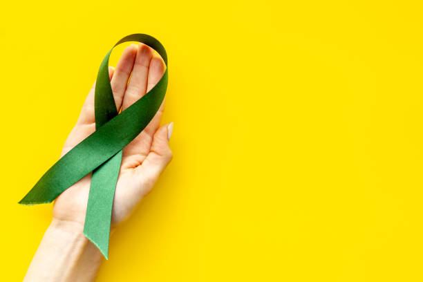 istock Green awareness ribbon in hands. Top view 1287428830