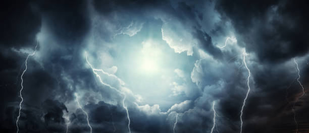 A dark stormy sky with dark clouds and lightning and the sun breaking through the clouds. stock photo