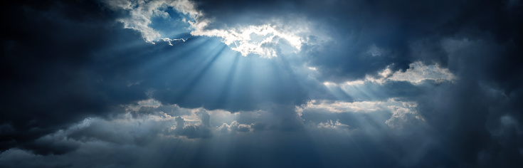 Panoramic view of clouds and sun with beautiful rays against the sky. Dramatic clouds after a storm, typhoon and sunbeams as a symbol of hope and faith.