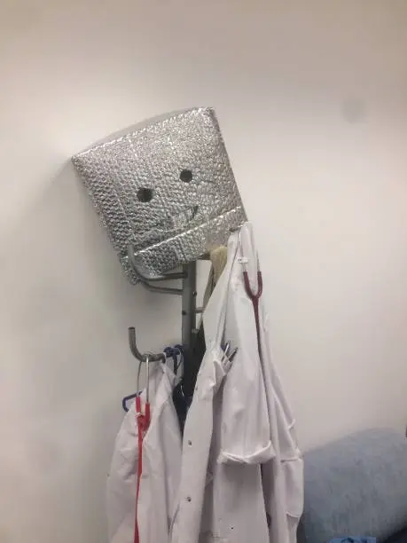 Doctor’s overall on hatstand with robot head silver box