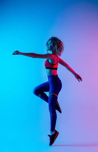 istock Young sportive woman training isolated on gradient pink-blue studio background in neon light. 1287432452