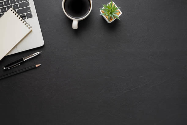 istock Top view above of Black office desk table with keyboard, notebook and coffee cup with equipment other office supplies. Business and finance concept. Workplace, Flat lay with blank copy space. 1287432723