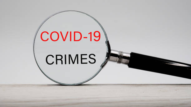 istock words covid-19 crimes through a magnifying glass. 1287435332