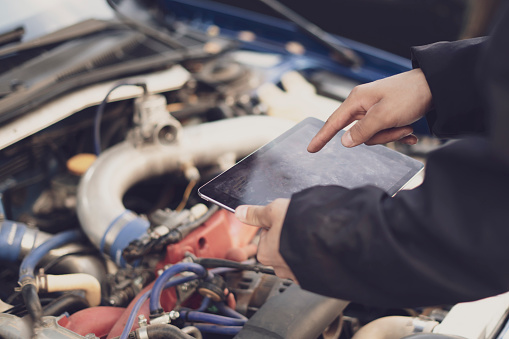 car mechanic doing auto diagnostic using computer, searching for check engine