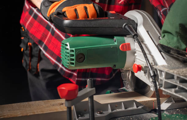 Closeup of young man sawing lumber with sliding compound miter saw indoors. Closeup of young man sawing lumber with sliding compound miter saw indoors. miter saw stock pictures, royalty-free photos & images