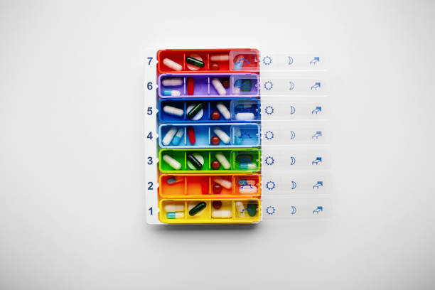 colorful daily pill organizer on plain white background. - pill box imagens e fotografias de stock
