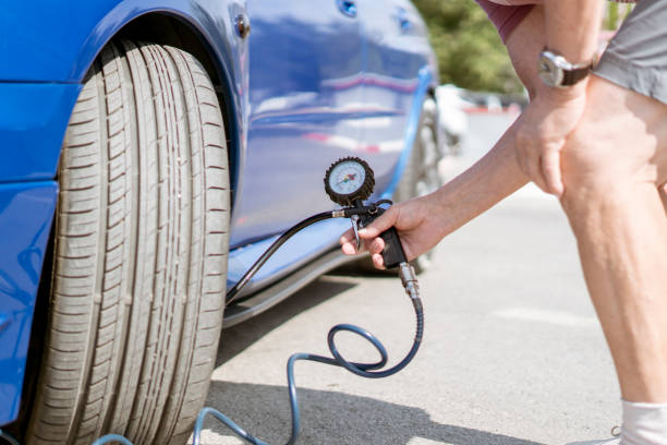 person pump up the car wheels tires with a compressor with manometer stock photo