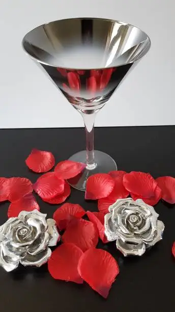 Silver cocktailglass, silver roses and red rose petals