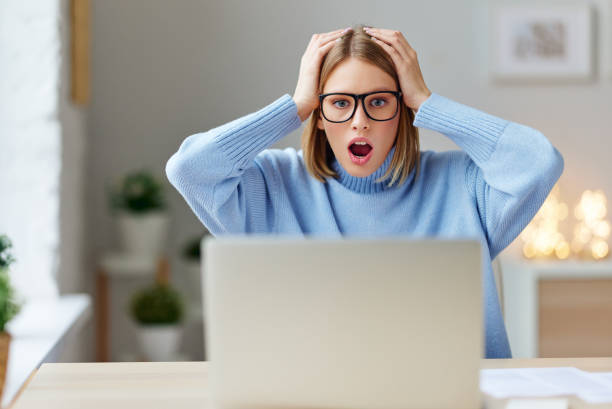 istock Shocked young woman using laptop 1287437625