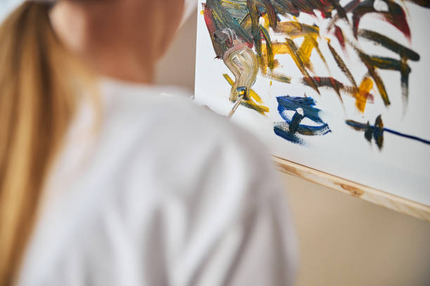 istock Girl with a ponytail painting with a brush 1287439272