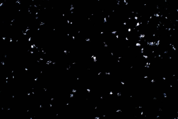 istock Abstract black background with isolated snowflakes. 1287439359