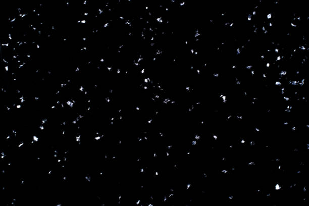 Abstract black background with isolated blurred snowflakes.