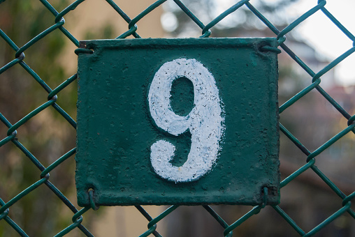 Old retro weathered cast iron plate with number 9 closeup