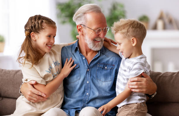 istock Grandfather hugging grandchildren on sofa 1287441416