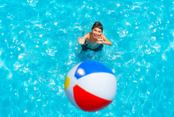 istock Little boy stand in pool and throw inflatable ball 1287445153