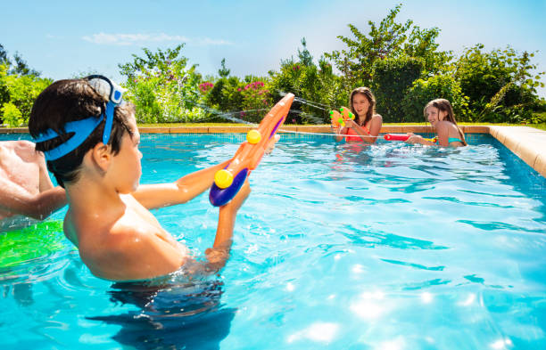 istock Kids in swimming pool shooting with water gun 1287445167