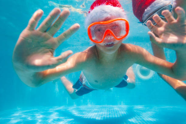 istock Two happy boys on vacation dive in Santa hat 1287445173