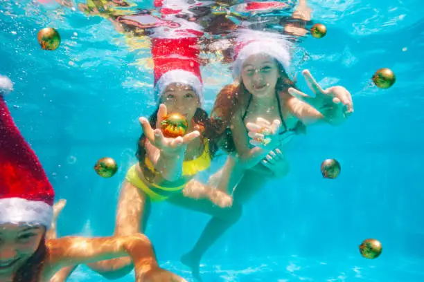 Photo of Two girls dive with Christmas tree balls in pool
