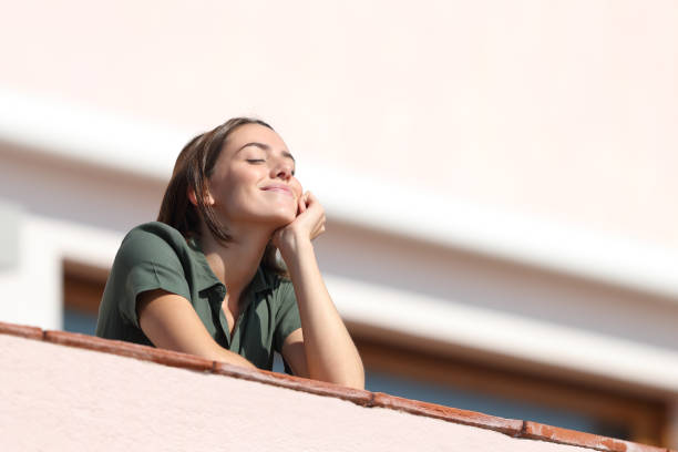 glückliche frau atmen frische luft vom balkon in der wohnung - ausatmen stock-fotos und bilder