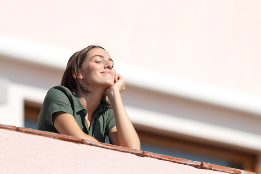 Mujer feliz respirando aire fresco desde el balcón en el apartamento photo