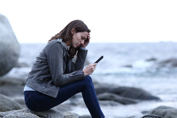 Sad teen checking smart phone message on the beach