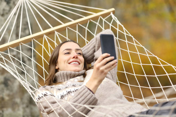 istock Happy woman checking phone on a hammock on holiday 1287446527